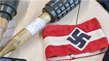 Sichergestellte Handgranaten und Materialien, darunter auch eine Armbinde mit einem Hakenkreuz, liegen bei einem Pressetermin im LKA Brandenburg auf einem Tisch nach einer Razzia gegen die Neonazi-Gruppe "Freie Kräfte Prignitz".