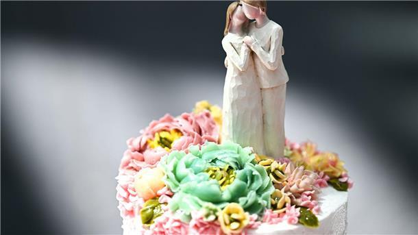 Ehepaare trauen sich kirchlich unter Kerzenschein Eine Figur, die einen Mann und eine Frau darstellt, steht auf einer Hochzeitstorte.