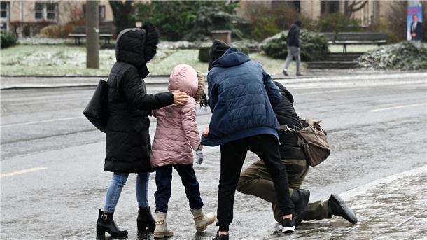 Glatteis: Deutschland rutscht in die Weihnachtswoche Einem Mann, der bei Eisglätte in Kassel vom Gehweg auf die Straße gestürzt ist, wird aufgeholfen.