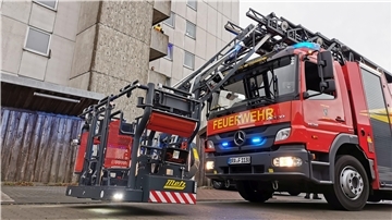 Ein Feuerwehrauto steht mit eingeschaltetem Blaulicht und Drehleiterkorb vor einem Hochhaus in Nordenham.