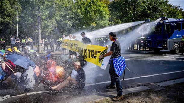 Einsatz von Wasserwerfern gegen Klimaaktivisten, die eine Straße blockieren.
