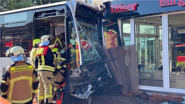 Einsatzkräfte der Feuerwehr untersuchen den  Linienbus, der zuvor in einen Dönerladen gekracht war.