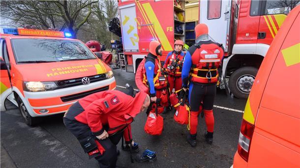 Feuerwehr rettet Radfahrer von überschwemmter Straße Einsatzkräfte der Wasserrettung der Feuerwehr stehen bei einem Einsatz auf einer überfluteten Straße.
