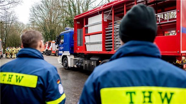 Einsatzkräfte des Technischen Hilfswerks (THW) stehen vor einem LKW.