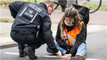 Einsatzkräfte lösen den Klebstoff, mit dem sich eine Aktivistin der Letzten Generation an der Straße festgeklebt hat. Die Klimaaktivisten blockieren so immer wieder den Verkehr. 