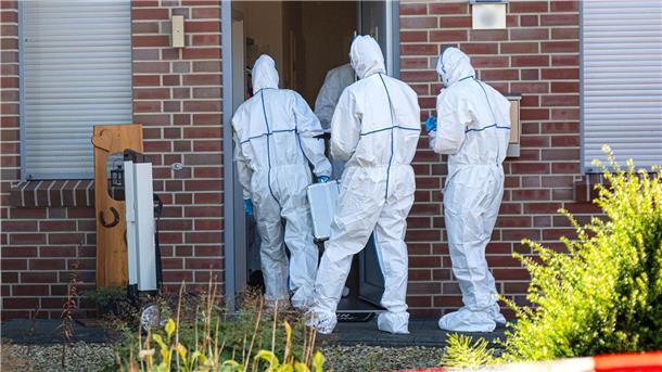 Männer in weißen Kitteln betreten ein Haus