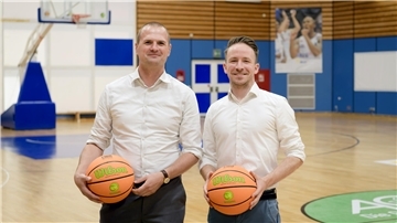 Zwei Männer stehen nebeneinander und halten einen Basketball in den Händen.
