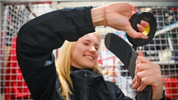 Eine Frau umwickelt einen Eishockeyschläger mit Klebeband.