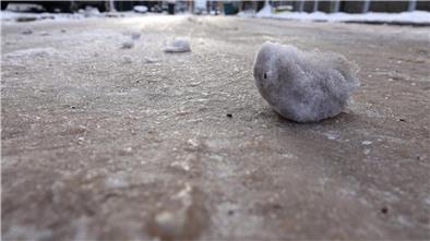 Eisklumpen liegen auf einer vereisten Straße.