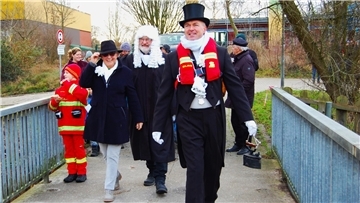 Eiswettschneider Christian Schwertfeger mit dem Bügeleisen in der Hand, Notarius Publicus Achim Thaler und Eiswett-Präsidentin Giesela Schwertfeger überqueren die Auebrücke.