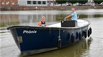 Zwei Menschen fahren in einem blauen Boot.