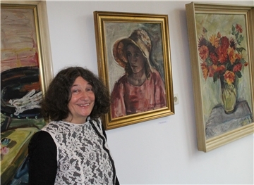 Eine Frau steht vor einer mit Bildern behangenen Wand.