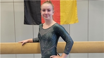 Eine Turnerin steht vor dem Balken