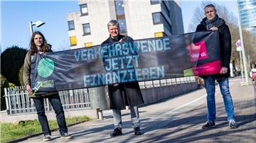 Emil Görtzen (l-r), Fridays for Future, Jürgen Schirmer, Gewerkschaft Verdi, und Patrick Steinbach, Verkehrsbetrieb BoGeStra, stehen mit einem Banner zum gemeinsamen Aktionstag vor der Verdi-Zentrale in Bochum.