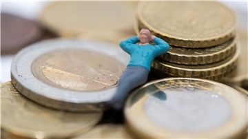 Die Figur einer Person liegt auf Euro-Münzen.