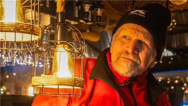 Ein Mann im Lichterschein einer Glühweinbude