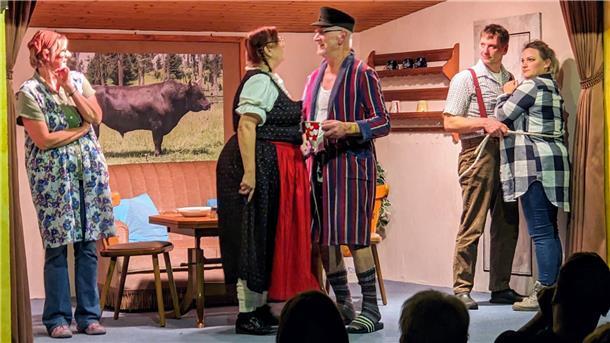 Drei Frauen und zwei Männer stehen auf einer Bühne in der Kulisse eines Wohnzimmers.