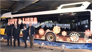 Vier Personen stehen vor einem Bus des öffentlichen Nahverkehrs.