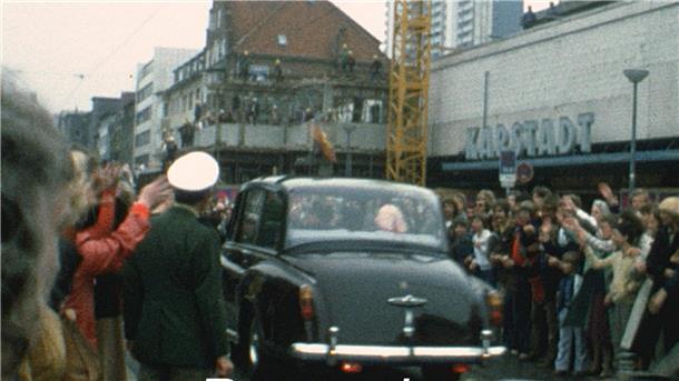 Foto stammt aus den 60er Jahren und zeigt ein Auto, umsäumt von jubelnden Menschen. 