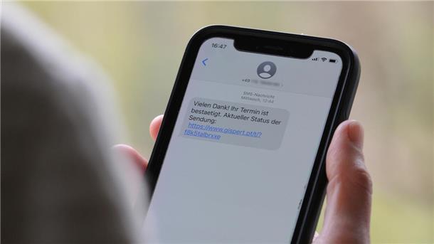 Ein Handy, auf dem eine SMS zu sehen ist. Das Handy wird in der Hand gehalten. Die Person ist nicht im Bild.