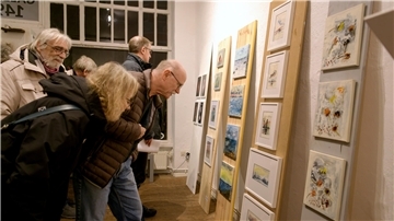 Menschen betrachten Kunstwerke an einer Wand