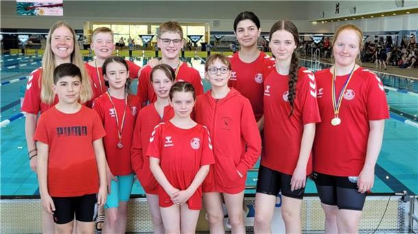 Eine Gruppe Schwimmer, Kinder und Jugendliche, steht vor dem Beckenrand.