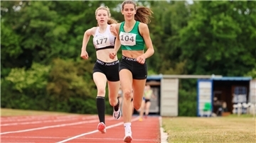 Zwei Leichtathletinnen umrunden die Bahn.