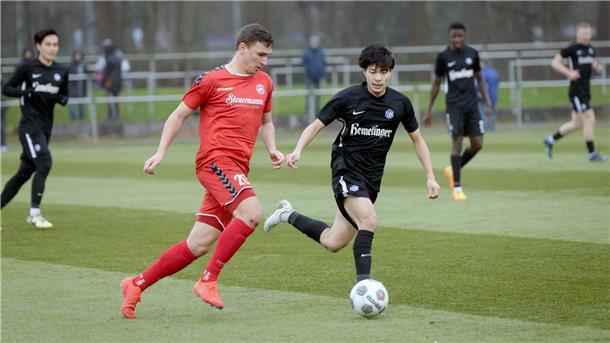Fußballer laufen einem Ball hinterher.