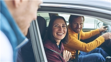 Das Foto zeigt ein junges Paar im Auto.