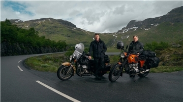 Ewan McGregor (links) und Charley Boorman mit ihren Motorrädern vor einer Landschaft. Auf ihrer Tour besuchten sie auch ein Schützenfest im Kreis Cuxhaven.