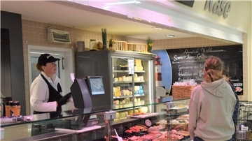Eine Fachkraft steht hinter einer Bedientheke im Markant-Markt in Ellwürden und berät Kunden bei der Fleischauswahl.  