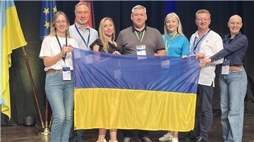 Gruppenfoto mit sieben Menschen, Frauen und Männern, die die Ukraine-Flagge in den Händen halten.