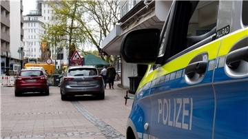 Fahrzeuge der Polizei stehen vor dem Wohnhaus des Tatverdächtigen im Fall des Messerangriffs in einem Duisburger Fitnessstudio.