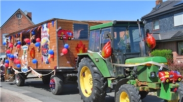 Ein Trecker zieht einen mit Luftballons geschmückten Anhänger