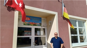 Ein Mann vor einem Eingang mit deutscher und türkischer Flagge.