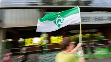 Feier vor dem Weserstadion: Ein Werder-Fan schwenkt voller Erleichterung die grün-weiße Fahne.