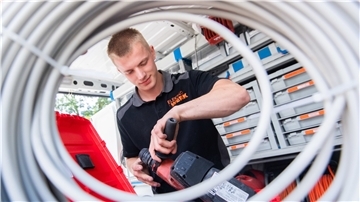 Felix Kuhlmann, Auszubildender vom Elektroinstallationsbetrieb Elektro Werk, hält Werkzeug (fotografiert durch eine Kabelrolle).