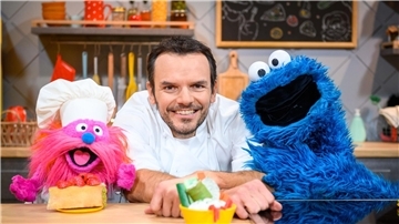 Fernsehkoch Steffen Henssler zwischen den Puppen „Gonger“ (l) und „Krümelmonster“ am Film-Set.