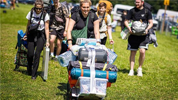 Festivalbesucher kommen mit ihrem Gepäck am Zeltplatz an.