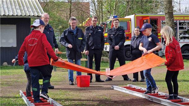 Feuerwehrdezernent Stadtrat Peter Skusa schaut sich zusammen mit dem Jugendfeuerwehrwart Jan Haucke und den Organisatoren Nathalie Zander und Thies Renken gespannt eine Station der Kinderflamme an.