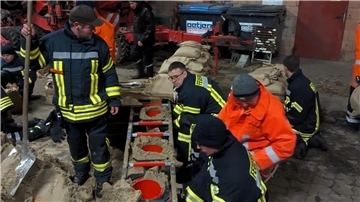 Feuerwehrleute füllen Sandsäcke. Dafür wurde unter einem trockenen und beleuchteten Unterstand eine „Sandsack-Füllstation“ eingerichtet.