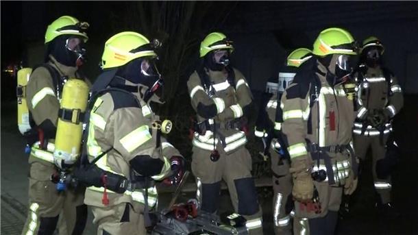 Brand in Ronnenberg verursacht halbe Million Euro Schaden Feuerwehrleute mit Atemschutzmasken stehen vor dem Mehrfamilienhaus in Ronnenberg.