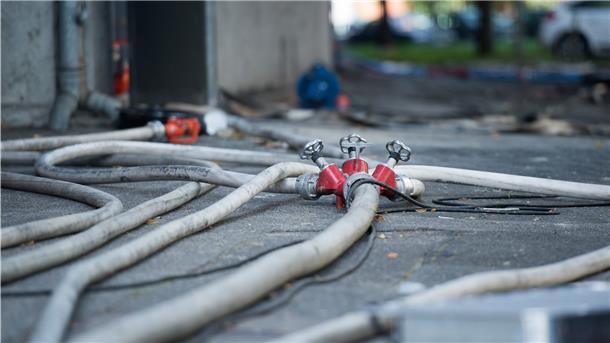 Feuerwehrschläuche liegen nach einem Brand auf der Straße.