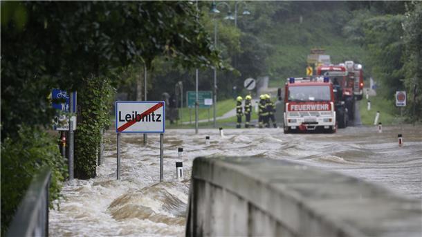 Feuerwehrwagen stehen vor einer überfluteten Brücke über die Sulm am Ortsausgang von Leibnitz in der Steiermark.