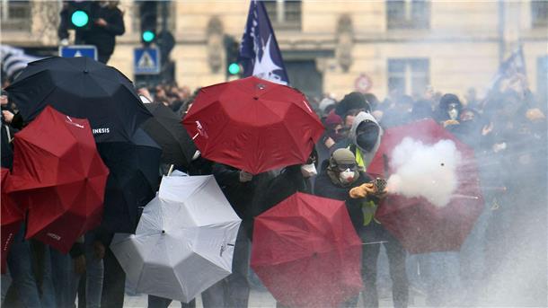 Rentenreform: Gewerkschaften wollen Frankreich lahmlegen Feuerwerkskörper werden abgeschossen, Menschen verstecken sich hinter Regenschirmen: Proteste in Nantes.