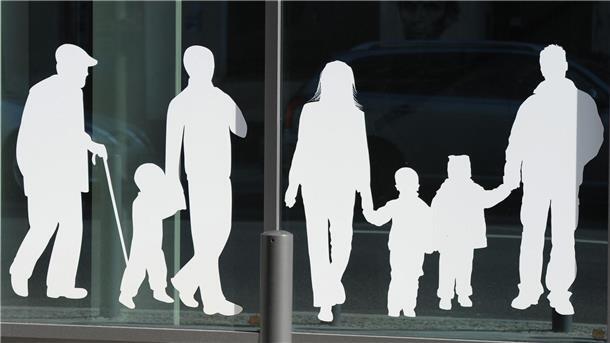 Figuren von Menschen in verschiedenem Alter sind auf Fensterscheiben aufgeklebt.