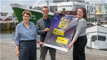 Drei Menschen zeigen ein Plakat