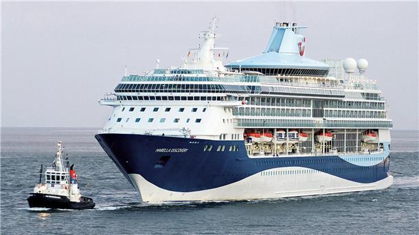 Ein Schlepper (links) begleitet ein blau-weißes Kreuzfahrtschiff. Fincantieri und TUI haben eine Absichtserklärung für zwei neue Kreuzfahrtschiffe unterzeichnet. Die umweltfreundlichen Neubauten sollen speziell auf den britischen Markt zugeschnitten sein. Zur Flotte gehören bislang fünf Kreuzfahrtschiffe - unter anderem die  „Marella Discovery“. 