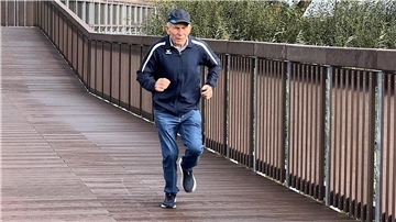 Ein Mann joggt über eine Brücke.