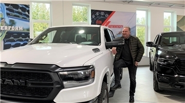 Ein Mann steht neben einem weißen DODGE RAM